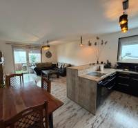 Obývací pokoj s kuchyní ve 3pokojovém bytě, podlaha s dřevěným dekorem.