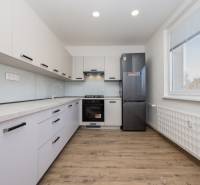 Kuchyně v 3-pokojovém bytě s podlahou s dřevěným dekorem a vybavením.