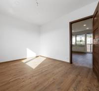 Pokoj s podlahou s dřevěným dekorem a bílými stěnami v 3-pokojovém bytě.