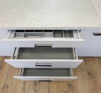 Otevírání kuchyňských zásuvek ve 3-pokojovém bytě s pracovní deskou a podlahou s dřevěným dekorem.