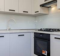 Kuchyně v 3-pokojovém bytě se sporákem a bílými skříňkami.