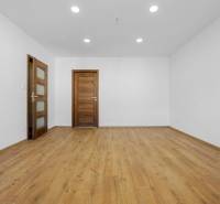 Pokoj v třípokojovém bytě s podlahou s dřevěným dekorem a dřevěnými dveřmi.