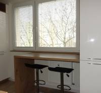 Kuchyně 3pokojového bytu s podlahou s dřevěným dekorem a velkými okny.