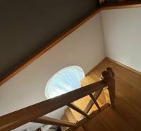 Schodiště s dřevěným dekorem v rodinném domě se schodišťovým zábradlím a kruhovým oknem.