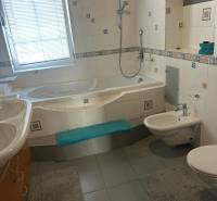 Koupelna v rodinném domě s vanou, bidetem a obklady.