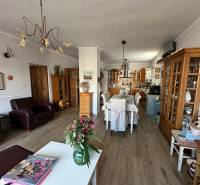 Obývací pokoj s kuchyní v rodinném domě, podlaha s dřevěným dekorem, květiny na stole.