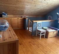 Podkroví rodinného domu s dřevěným stropem, stěnami a podlahou s dřevěným dekorem.