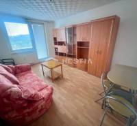 Obývací pokoj v 3-pokojovém bytě s pohovkou, stolkem a skříní, světlá podlaha.