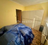 Pokoj se skříní, radiátorem a zakrytým nábytkem ve 3-pokojovém bytě.