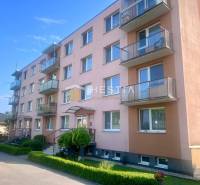 Čtyřpatrový bytový dům v Moravském Lieskovém s balkony a parkováním před budovou.