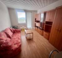 Pokoj v 3-pokojovém bytě s pohovkou, skříněmi a stolkem na světlé podlaze.