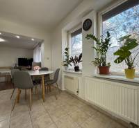 Jídelna v 2-pokojovém bytě s pokojovými rostlinami a kulatým stolem.