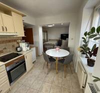 Kuchyně v 2-pokojovém bytě s kulatým stolem, rostlinami a spotřebiči.