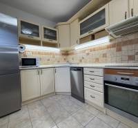 Kuchyně v 2-pokojovém bytě s myčkou, troubou, mikrovlnkou a kachličkovými obklady.