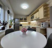 Kuchyně v 2-pokojovém bytě s kuchyňskou linkou, okny a rostlinami.