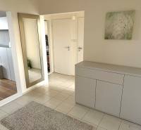 Předsíň ve 3-pokojovém bytě s bílým nábytkem, zrcadlem a podlahou s dřevěným dekorem.