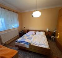 Ložnice v rodinném domě s dvěma postelemi, skříní a kobercem.