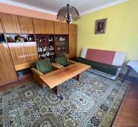 Obývací pokoj v rodinném domě s nábytkem, kobercem a obrazem na stěně.