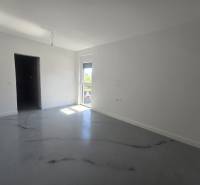 Prostorný pokoj ve vile s bílými stěnami a podlahou s dřevěným dekorem.