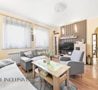 Obývací pokoj v rodinném domě s pohovkou, stolkem, televizí a podlahou s dřevěným dekorem.