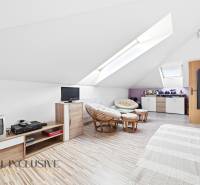 Podkrovní místnost v rodinném domě s křesly a podlahou s dřevěným dekorem.