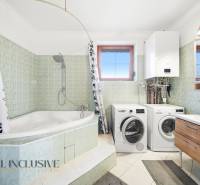 Koupelna s vanou, sprchou, pračkou a sušičkou v rodinném domě.