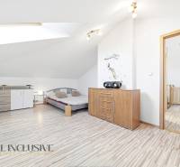 Světlá ložnice s podlahou s dřevěným dekorem, komodou a postelí v rodinném domě.