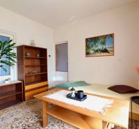 Obývací pokoj v rodinném domě s kobercovou podlahou, dřevěným nábytkem a obrazem pláže.