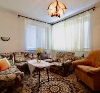 Obývací pokoj v rodinném domě s pohodlným čalouněným nábytkem a ozdobným kobercem.