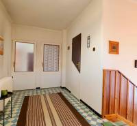 Rodinný dům se vzorovanou dlažbou, dřevěnými schody a jednoduchou dekorací stěn.