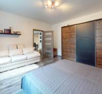 Ložnice v rodinném domě s prostornou skříní a podlahou s dřevěným dekorem.