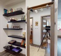 Interiér rodinného domu s otevřeným průchodem, knihovničkou a dřevěným dekorem podlahy.