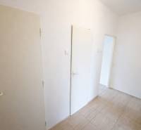 Chodba v 2-pokojovém bytě s bílými dveřmi a dlažbou.