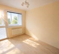 Pokoj s velkým oknem a podlahou s dřevěným dekorem v 2-pokojovém bytě.