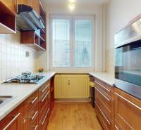 Kuchyně ve 3-pokojovém bytě s plynovým sporákem a podlahou s dřevěným dekorem.