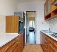 Kuchyně ve 3-pokojovém bytě s podlahou s dřevěným dekorem a světlými obklady.