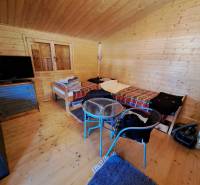 Pokoj se stěnami ze dřeva, postelemi, televizorem a podlahou s dřevěným dekorem.