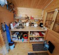 Dřevěná kuchyňka se spotřebiči, poličkami a dřezem v interiéru zahrad.