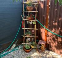 Zahrady v Dolních Krškanech v Nitře s ozdobným žebříkem a květináči na štěrkovém podkladu.