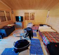 Pokoj v Zahradách se stolkem, židlemi a dvěma postelemi s barevnými přikrývkami.