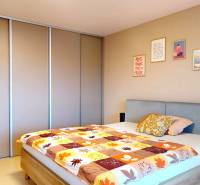 Ložnice v rodinném domě s postelí, vestavěnou skříní a dekorativními obrazy na stěně.