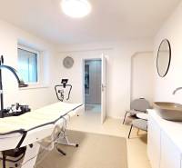 Interiér rodinného domu s masážním stolem, umyvadlo, zrcadlo a židle.