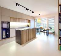 Otevřená kuchyně s jídelním stolem a knihovničkou v rodinném domě.