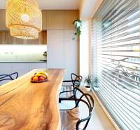 Kuchyně v rodinném domě s masivním stolem a závěsným svítidlem.