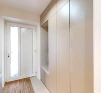 Vstupní chodba rodinného domu s věšákovou skříní, zrcadlem a kobercem.