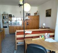 Pokoj v 2-pokojovém bytě s nábytkem, postelí a dekoracemi na policích.