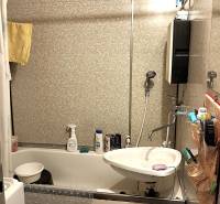 Koupelna v 2-pokojovém bytě s vanou, umyvadlem a obloženými stěnami.