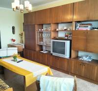 Obývací pokoj v 2-pokojovém bytě s nábytkem v dekoru dřeva a retro televizorem.