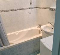 Koupelna v 2-pokojovém bytě s vanou a světlými obklady.