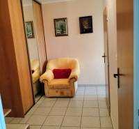 Křeslo u vchodových dveří s dlaždicovou podlahou ve 2-pokojovém bytě, zrcadlová skříň.